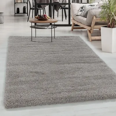 A shaggy gray rug in a living room setting, with a coffee table and furniture in the background.