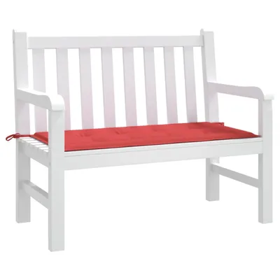 A white garden bench with a red cushion.