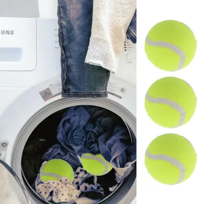 A washing machine with laundry inside, and three tennis balls on the right side.