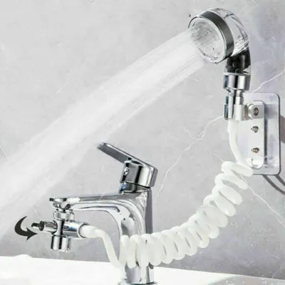 A shower head attachment for a faucet is shown spraying water.