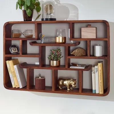 A wooden wall shelf filled with various decorative items and books.