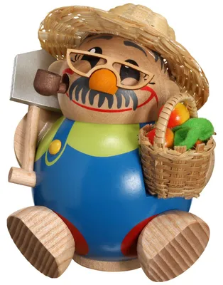 Ein fröhlicher Gärtner aus Holz trägt eine bunte Latzhose und einen Strohhut hält einen Spaten in der einen Hand und ein Körbchen mit Äpfeln in der anderen und hat eine Brille sowie eine Pfeife im Mund