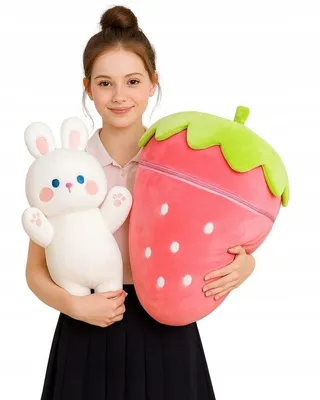 A young girl holding a white rabbit plush toy and a large strawberry-shaped plush toy.