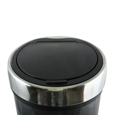 A close-up view of the top of a trash can with a silver rim and a black lid.