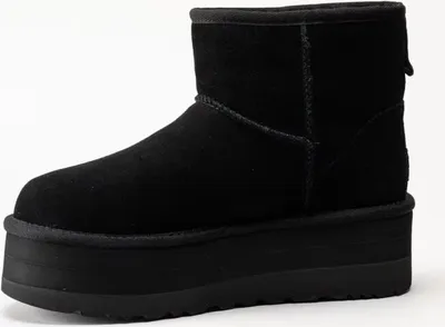 A black UGG boot with a platform sole is shown against a white background.