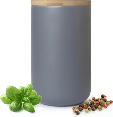 A gray ceramic storage jar with a wooden lid, shown with a sprig of basil and peppercorns.