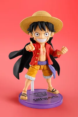 A figurine of Monkey D. Luffy from One Piece stands on a purple display base against a pink background.