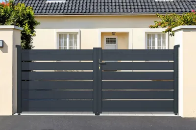 A double-leaf aluminum gate in front of a house.