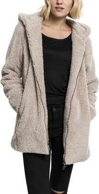 A woman wearing a beige sherpa jacket and black pants.