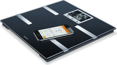 A digital body analysis scale with a smartphone placed on it, displaying health data.