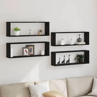 Four black rectangular wall shelves are mounted on a white wall above a sofa. The shelves are decorated with various items.
