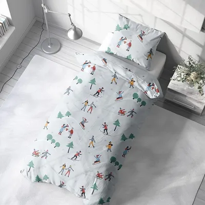 A child's bed with winter-themed bedding in a bright, airy room.