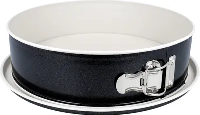 A black springform cake pan with a white interior and a silver latch mechanism, shown from a slightly elevated side angle on a white and gray surface.