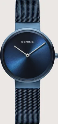 A close-up studio shot of a blue Bering watch with a mesh band against a light gray background.