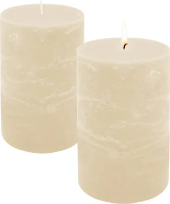 Two cream-colored pillar candles on a white background, one with a lit flame.
