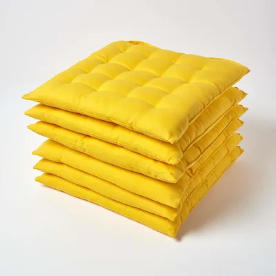 A stack of six yellow seat cushions on a white background.