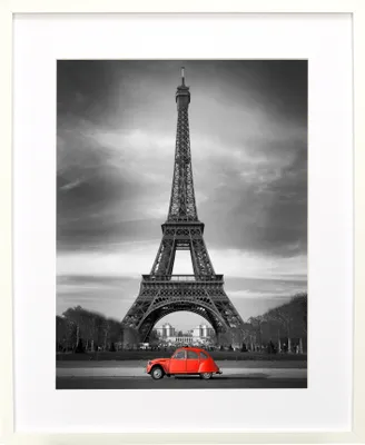 A framed black and white photograph of the Eiffel Tower with a red car in the foreground.