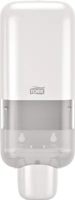 A white Tork soap dispenser mounted on a wall.
