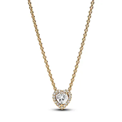 A close-up studio shot of a gold necklace with a heart-shaped pendant.