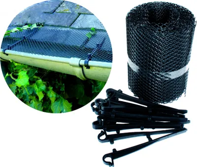 A close-up view of a gutter guard system installed on a roof gutter, with a roll of gutter guard mesh and clips shown in the foreground.