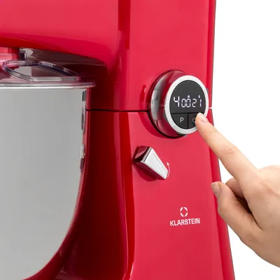 A close-up shot of a red kitchen mixer with a hand pressing a button on its digital display.