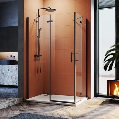 A modern bathroom with a black framed glass shower enclosure, orange tiled walls, and a fireplace.