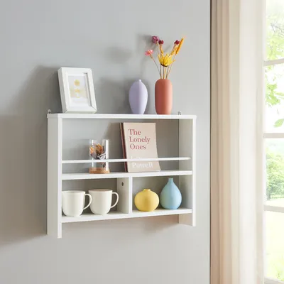 A white wall-mounted shelf with various decorative items and mugs.