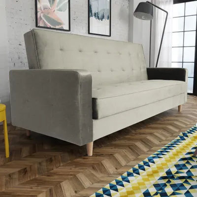 A sofa is shown in a room with a wooden floor and artwork on the wall.