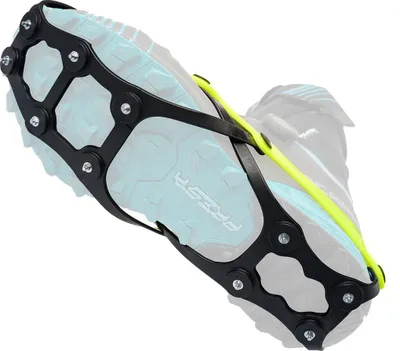 Schwarze Schuhkralle mit Metallstiften und gelbem Spannband auf der Sohle eines Sportschuhs