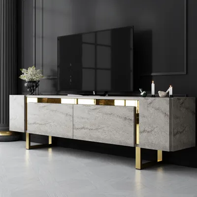 A modern TV stand with a marble-like finish and gold accents, displayed in a dimly lit, luxurious room.