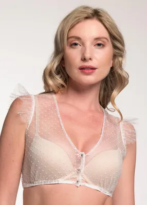 A woman is shown wearing a white sheer top with polka dots over a beige bra.