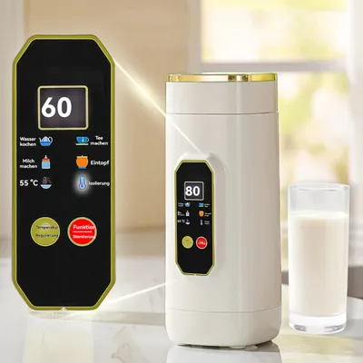 A white electric travel kettle with a gold rim sits next to a glass of milk, with a separate control panel displayed to the left.
