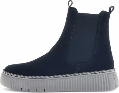 A side view of a single blue Chelsea boot with a thick gray sole.