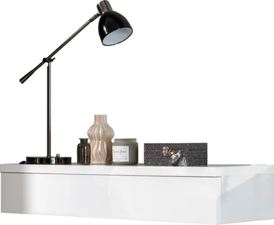A white console table with decorative items on top, including a lamp, vases, and a candle.