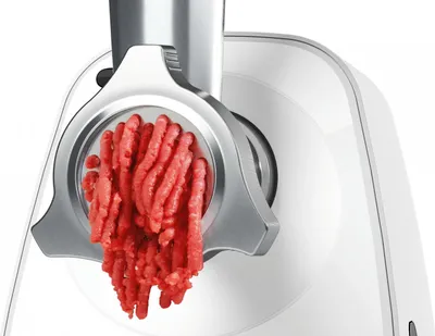 A close-up of a meat grinder with ground meat coming out of it.