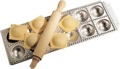 A ravioli maker with a rolling pin and several ravioli.