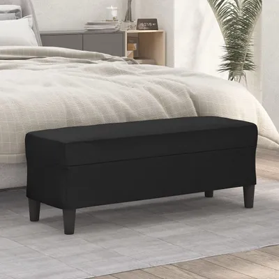 A black storage bench is placed in front of a bed in a bedroom.