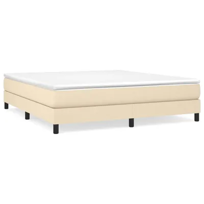 A studio shot of a cream-colored box spring bed frame with a white mattress on top, set against a white background.