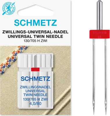 A package of Schmetz twin sewing needles and the needles themselves are displayed against a light brown fabric background.