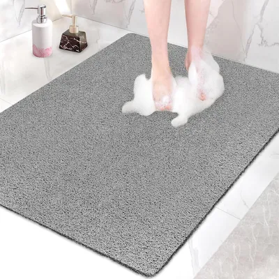 A person's feet are stepping onto a gray bath mat, creating foam.