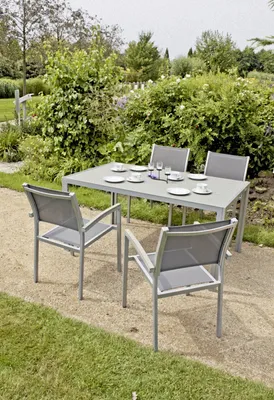 A dining set with chairs and a table is placed outdoors in a garden setting.