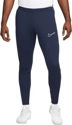 A man is wearing navy blue Nike training pants and white sneakers.