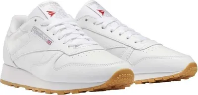 A pair of white Reebok Classic Leather sneakers with gum soles, shown from a slightly elevated side angle.