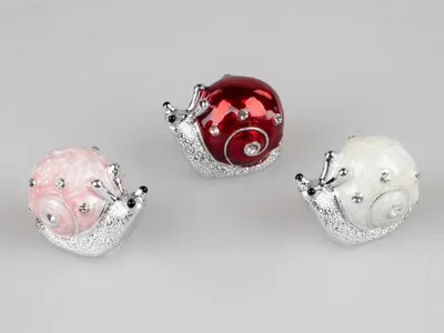Three decorative snail figurines in different colors are arranged on a light gray background.