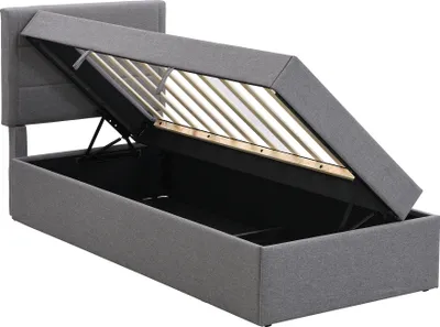 A grey upholstered bed frame with the mattress support mechanism open, revealing the storage space underneath.