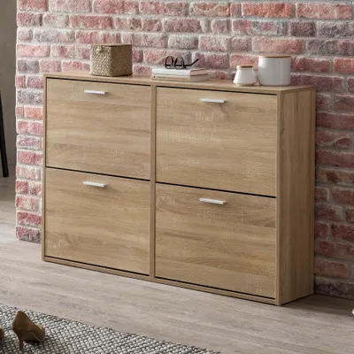 A wooden shoe cabinet with four flip-down drawers is shown against a brick wall. Decorative items are on top of the cabinet.