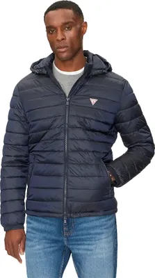 A man wearing a dark blue puffer jacket and blue jeans, posing against a white background.