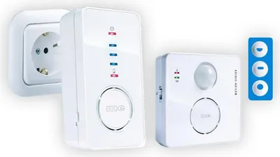 A white electronic device plugged into a wall socket, next to another white electronic device, with a blue icon to the right.
