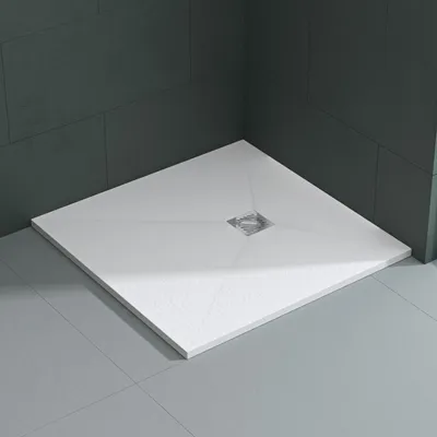A white square shower tray with a silver drain in the center, set in a corner with dark gray tiled walls and light gray tiled floor.