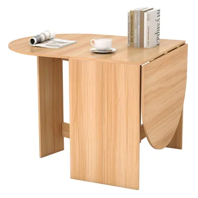 A light wood folding dining table with books and a cup of coffee on it.